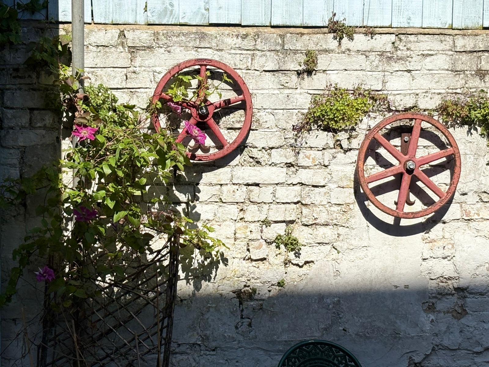 The secret garden at The Book Hotel — vintage wheels on stone wall with clematis